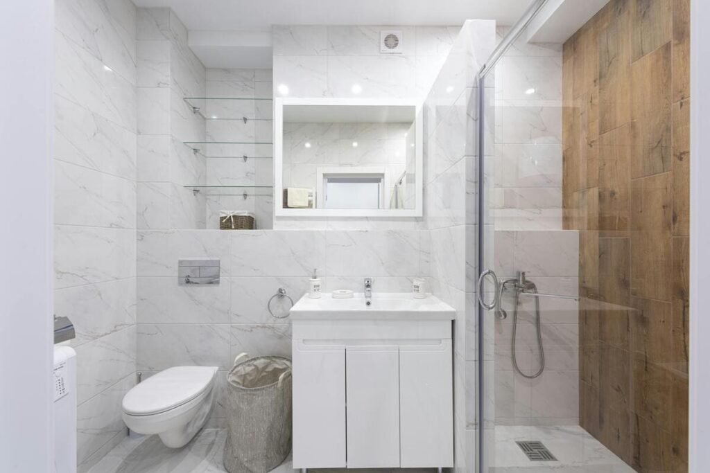Pristine white bathroom with marble tile and gold fixtures